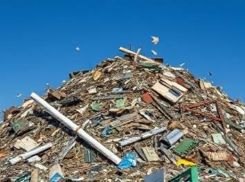 chaotic Apopka rubbish heap, unsettling, towering, photorealistic, a mountain of trash against clear blue skies, highly detailed, windblown debris occasionally lifting, telephoto shot, somber hues of gray and rust, harsh midday light, shot with a 200mm camera lens.
